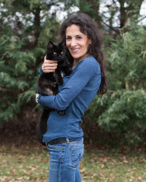 Woman holding black cat in her arms outside