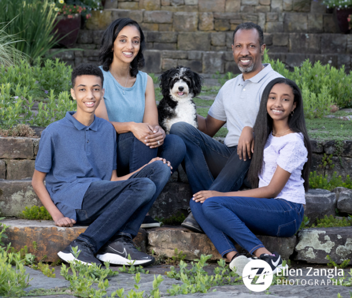 Family of four sitting with their dog outside.