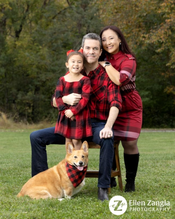 Family with three people and one Corgi dog outside in the fall.