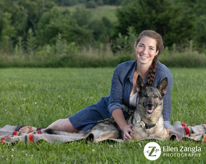 Portrait of a woman sitting outside on a blanket with her German Shepherd dog.