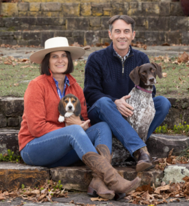 Couple sitting outdoors for a fall family photo with two dogs, a Beagle puppy and a German Short-Haired Pointer.