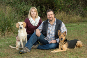 Man and woman with two dogs outdoors in Northern VA for family photo.
