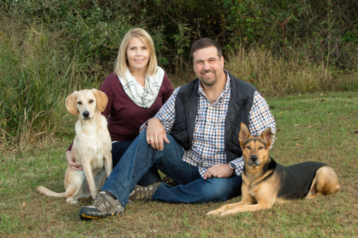 Man and woman with two dogs outdoors in Northern VA for family photo.
