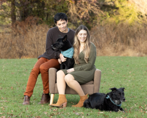Family photo with two people and two black dogs outdoors in Loudoun County, VA.