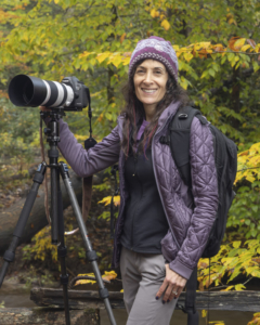 Ellen Zangla, pet photographer, standing outside in the fall with her camera and tripod.