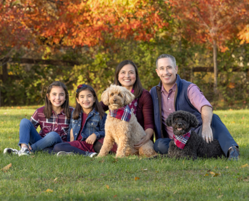 Family photo with two adults, two kids, and two dogs outside in the fall in Loudoun County.