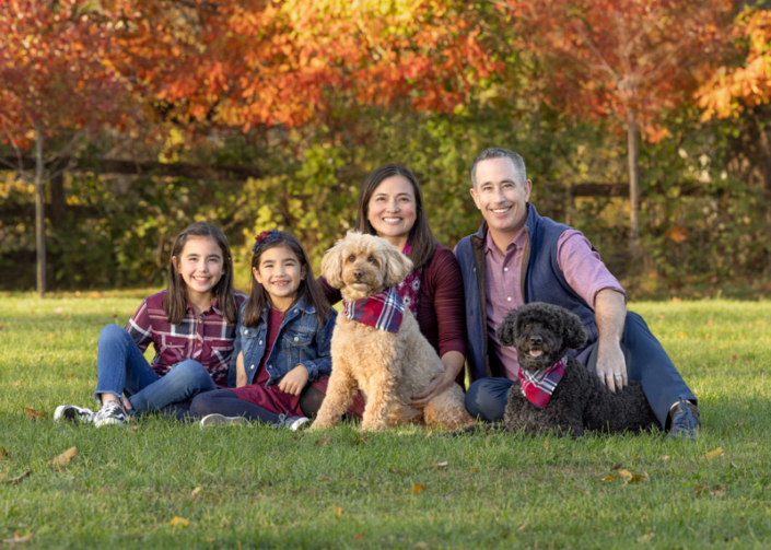Family photo with two adults, two kids, and two dogs outside in the fall in Loudoun County.