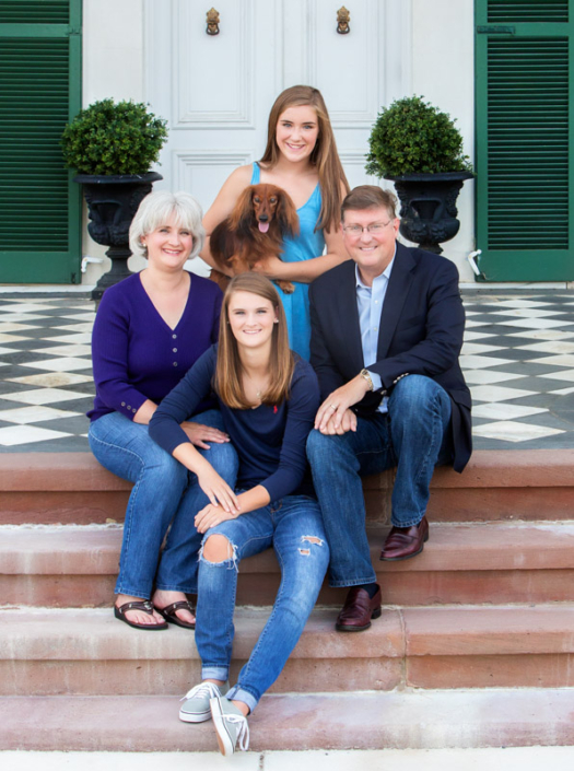 Family of four with their dog sitting outside on the steps in front of the mansion at Morven Park in Leesburg, VA.