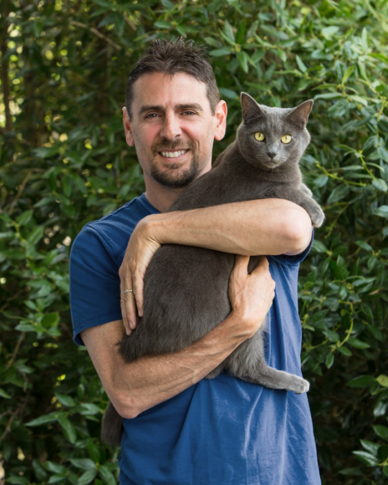 Man holding gorgeous gray cat in his arms outdoors in Loudoun County, VA.