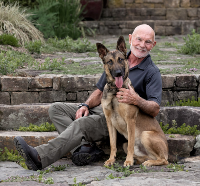 Man seated outside with his Belgian Malinois in Northern Virginia.