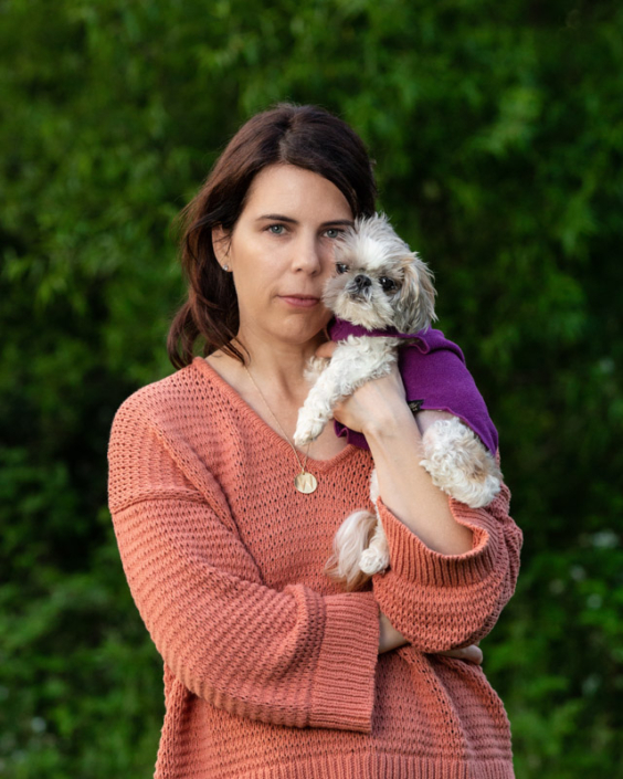 Woman outside holding small dog close to her face in Loudoun County, VA.