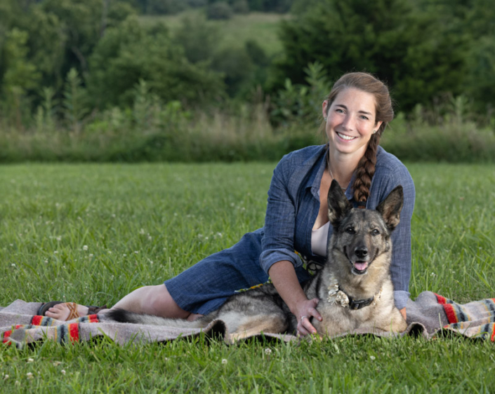 Woman sitting outside on a picnic blanket with her German Shepherd Dog in Loudoun County, VA.