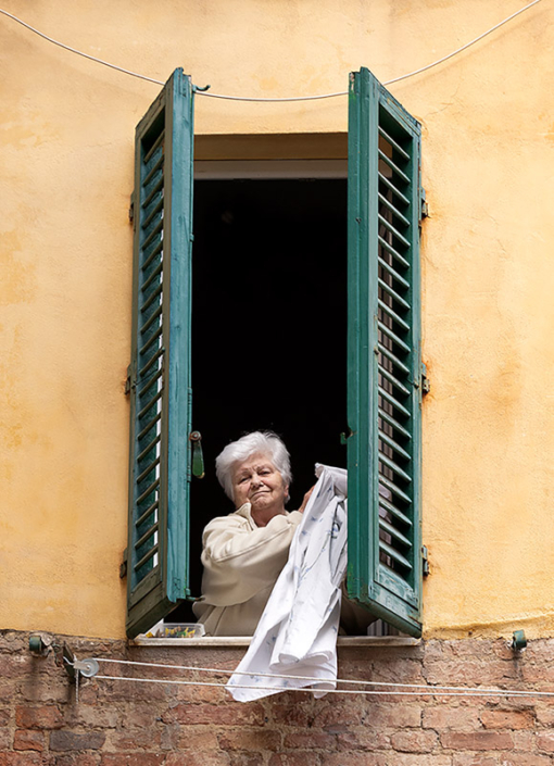 Woman bringing laundry in to her house in Siena, Italy.