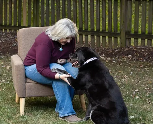Woman Holding Dog's Paw | Ellen Zangla Photography Woman holding her black Lab's paw outdoors in Northern Virginia
